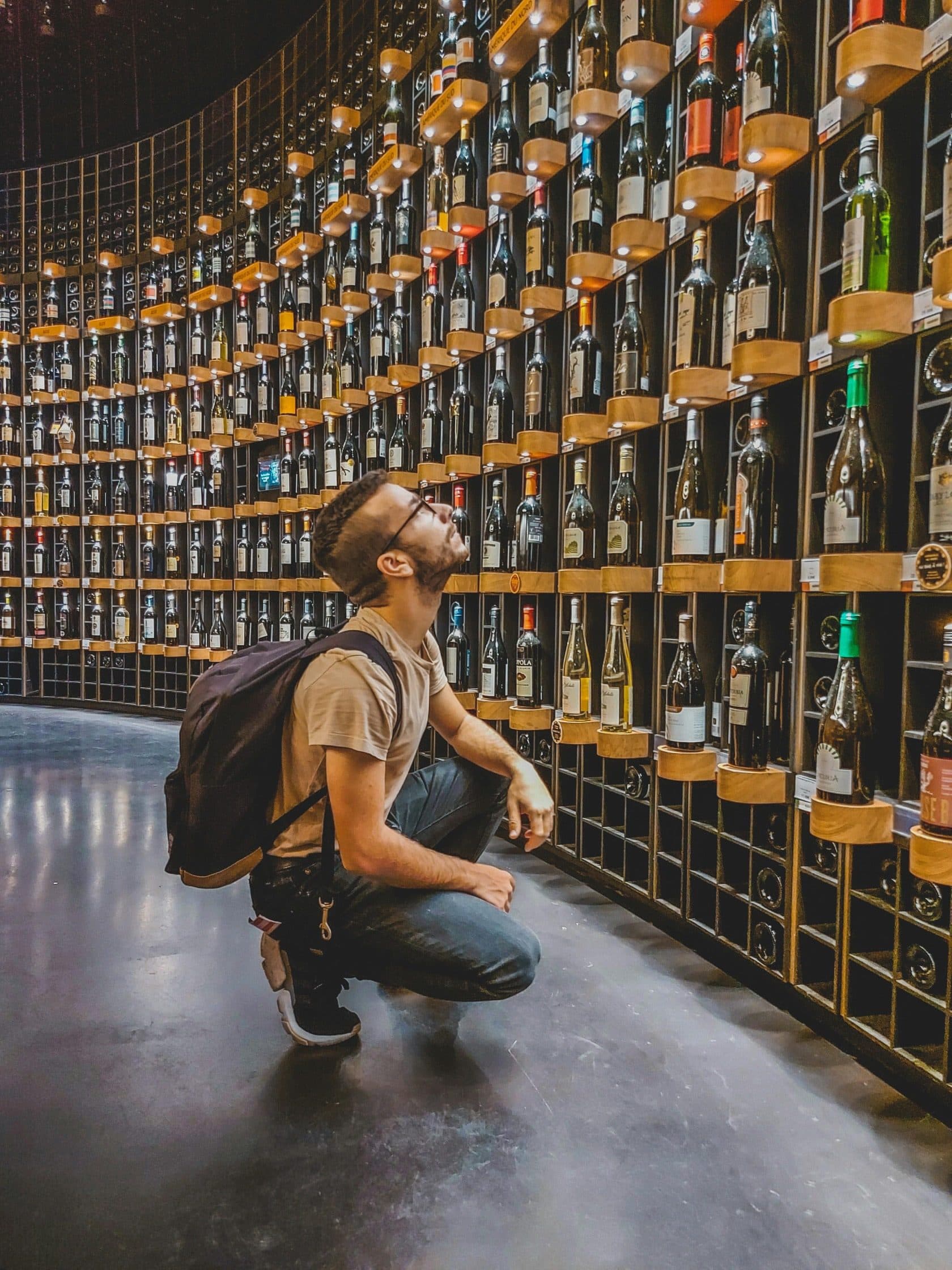 Bodega con botellas de vino en estantes de madera, iluminación cálida